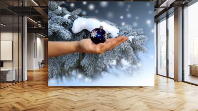 female hand with a christmas sphere on a background of a blue sp Wall mural