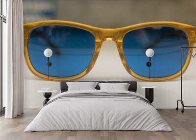 Glasses with blue glasses & yellow frame are on a table. Blue is the symbol of a dream. Yellow is a symbol of a happy outlook on life. Your glasses are your character. Wall mural