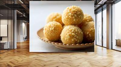 Golden Indian sweet balls with sesame seeds on ornate plate symbolizing festive indulgence Wall mural