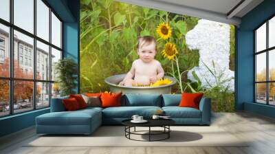 Cute baby girl in a basin on a sunflower field Wall mural