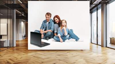 Happy family Father, mother and child lying on the floor with laptop on white background isolated Wall mural