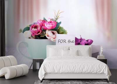 Happy mothers day gifts with red white roses in a cup, and gift tag with text „For the best mom“, presented on wooden table with bright backround Wall mural