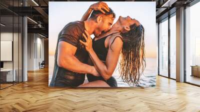 Happy young fit couple in sea or ocean hug each other with love at summer sunset. Romantic mood, tenderness, relationship, vacation concept. Wall mural