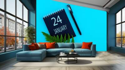 January 24th. Day 24 of month, Calendar date. Black notepad sheet, pen, fern twig, on a blue background. Winter month, day of the year concept Wall mural