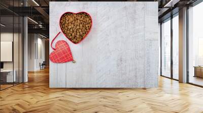 Heart shaped bowl with food for pets and red heart toy on wooden background. With love for animals concept and Valentine's Day. Top view. Copy space Wall mural