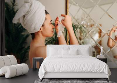 Young beautiful asian woman making face mask in the bathroom in front of the mirror. Wall mural