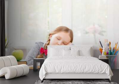 Little student girl sitting at the table, fell asleep at the books. Blurred background. The concept of education and school. Wall mural