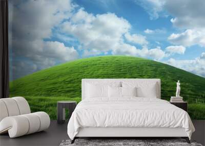 Lush green hill under a cloudy blue sky. Wall mural