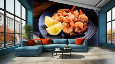 Skillet roasted jumbo shrimp on a black plate. Closeup. Shrimp roasted with sliced garlic and spices. Wall mural