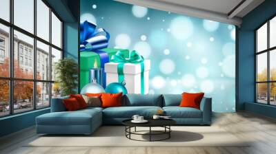 Holiday illustration with several colored gift boxes with ribbons and bows, burning candles and Christmas balls on a blurred background with bokeh effect in blue colors Wall mural