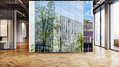 Part of modern corporate buildings from glass with reflections of green trees. Green building concept. Wall mural