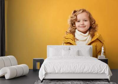 Portrait happy little girl preschooler in a winter jacket. Yellow on a yellow background. Wall mural