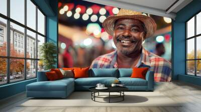 Portrait  smiling Brazilian senior man in a plaid shirt and straw hat on the background of a festive celebration party Festa Junina. Summer, night, street city,  Garland. Traditional holiday concept. Wall mural