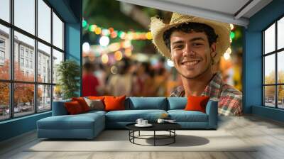 Portrait  smiling Brazilian young man in a plaid shirt and straw hat on the background of a festive celebration party Festa Junina. Summer, night, street city,  Garland. Traditional holiday concept. Wall mural