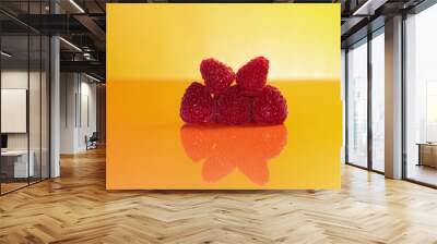 Five ripe raspberries on an orange background. Wall mural