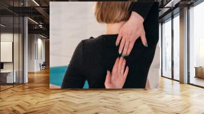 A girl in a black yoga jumpsuit performs yoga asson. Blue yoga mat n the yoga studio Wall mural