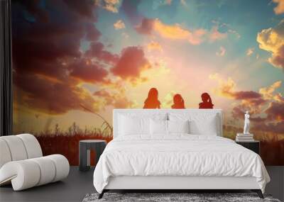 Silhouettes of children holding hands under a sunset sky. Wall mural