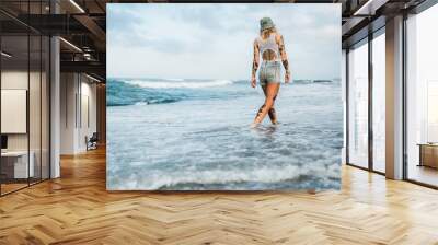 Tattooed woman walking at beach Wall mural