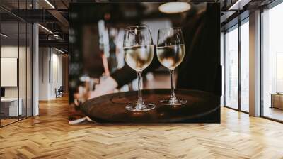 Two glasses of white wine glasses on the black tray, carried by a waiter. Restaurant, catering and celebraiton concept. Wall mural