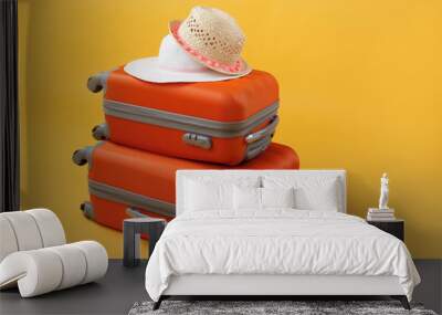 Two lying suitcases of travel bags and straw hats on a yellow background with copy space. The concept of summer time, vacation, tourism. Wall mural