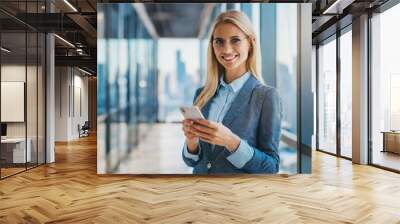 Young caucasian female project manager in skyscraper office building, using smartphone Wall mural