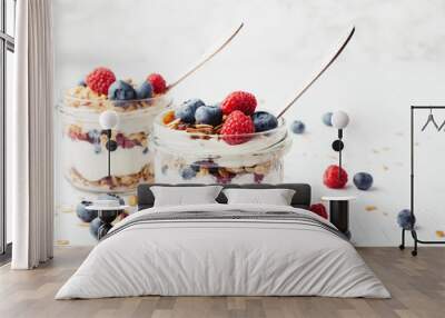 Two jars with tasty parfaits made of granola, berries and yogurt on white wooden table. Shot at angle. Wall mural