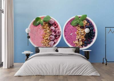 Two smoothie bowls with granola, blueberries, raspberries and mint on blue background. Healthy breakfast, top view. Wall mural