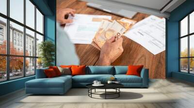 Man handling euro bills while reviewing utility expenses and household finances. Emphasis on financial planning, tax calculations, and managing payments online  Wall mural