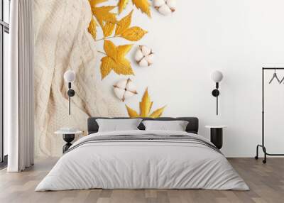 Flat lay autumn composition. Knitted woolen light beige sweater or plaid, golden dry leaves, cotton flowers on white background top view copy space. Autumn, fall concept Wall mural