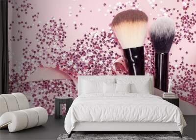 Two different Cosmetic makeup brushes with pink ribbon and holographic glitter confetti in the form of stars on pink background Flat lay top view copy space Makeup accessories holiday birthday newyear Wall mural