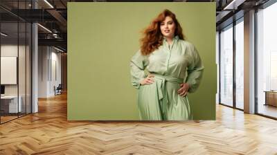 confident and calm beautiful happy red hair woman plus size model posing on green background Wall mural