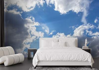 Beautiful blue sky with white clouds of an unusual shape. Clear summer sky with puffy cumulus clouds, heavenly landscape with sunbeams. Background wallpaper backdrop Wall mural