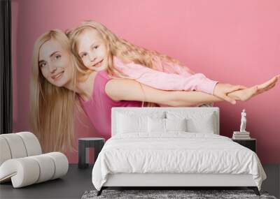 mother with daughter in pink clothes on a pink background Wall mural