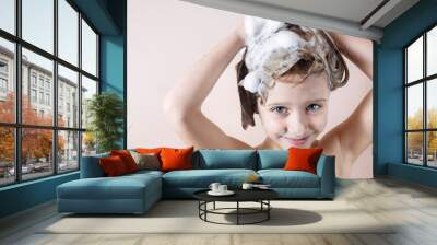 adorable little girl with blue eyes washing her hair in the bathroom and laughs, foam on the head, look at the camera Wall mural