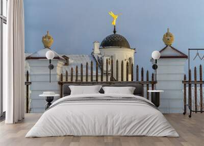 A golden angel playing the trumpet on one of the towers of the Tobolsk Kremlin (Russia) against the background of a blue cloudy sky. antique fence with white relief posts, vases on them  Wall mural