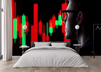 A man wearing glasses is looking at a graph on a screen. The graph is red and green, and it is a stock market chart. The man seems to be focused on the chart Wall mural