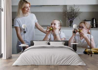 Mom and two daughters in white at the table. Wall mural