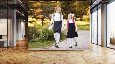 Two girls Schoolgirls go on the road in the autumn Park and talking to each other Wall mural