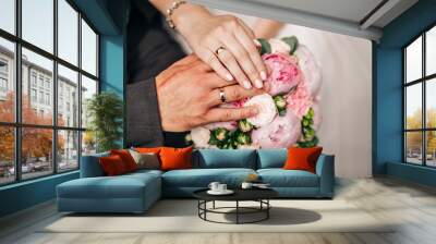 Hands of the bride and groom with wedding gold rings lie on a bouquet of flowers Wall mural