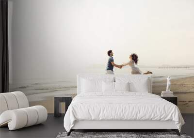 Happy couple in love has fun on the beach. They jump, laugh and enjoy the sea Wall mural