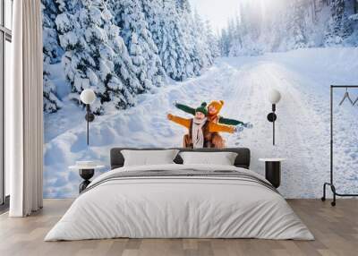 Happy funny children ride wooden retro sleds on snowy road in mountains. Family on winter walk. Wall mural