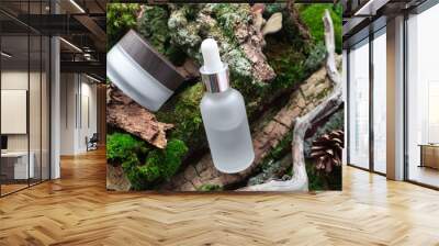 Serum bottle with pipette and facial or eye cream on forest background. Concept bio organic beauty product with natural extract. Eco cosmetic transparent skincare and body care Wall mural