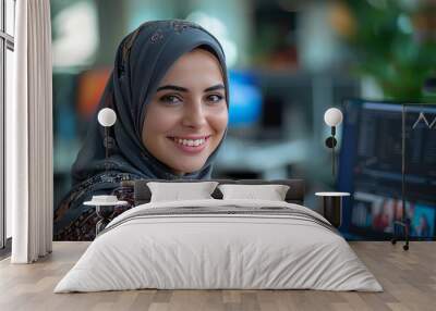 Smiling portrait of a businesswoman of arab descent wearing a hijab working with computer on desk in a startup company in a modern business office Wall mural