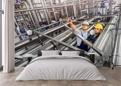 Two young engineers inspect an industrial plant for the treatment of contaminated water. Top view on engineering structures. Factory workers solve problems. Wall mural