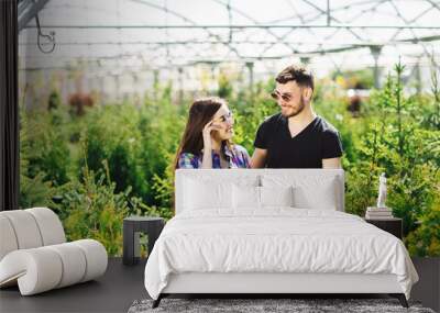 Young couple, man and woman, standing together in the garden center and choose plants for greening the house Wall mural