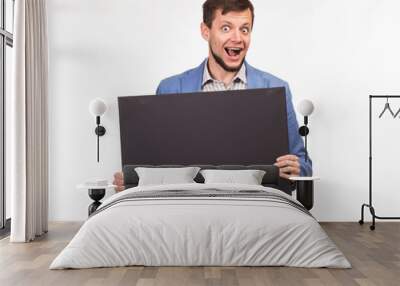 Young happy man portrait of a confident businessman showing presentation, pointing paper placard gray background. Ideal for banners, registration forms, presentation, landings, presenting concept. Wall mural