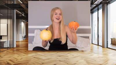 beautiful blonde with two pumpkins in white bedroom. halloween concept. Wall mural