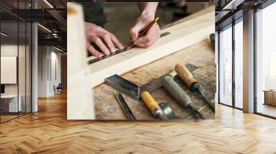 The worker makes measurements of a wooden board with ruler. Wall mural