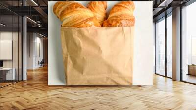 Freshly baked French buttery flaky croissants in brown paper bag on white background. Minimalist creative food banner with copy space Wall mural