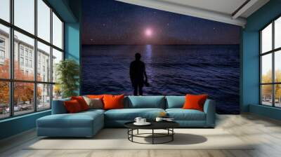 composition person in water ocean looking at night sky falling stars and moon Wall mural